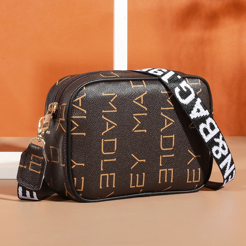 A brown leather fashion crossbody shoulder bag with gold hardware and a black and white striped strap.
