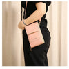 A woman holds a light pink leather touchscreen crossbody shoulder bag against a neutral background.