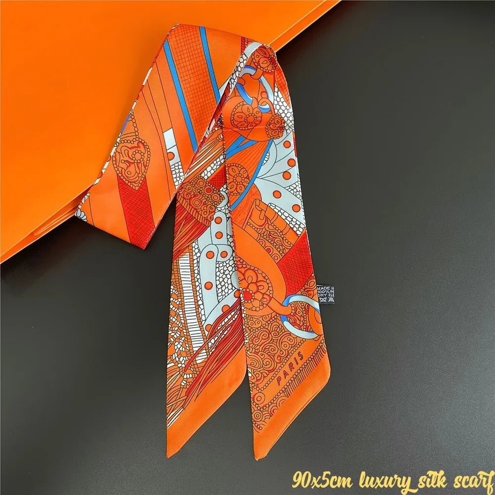 Orange silk scarf with intricate orange and white patterns displayed against a dark background.