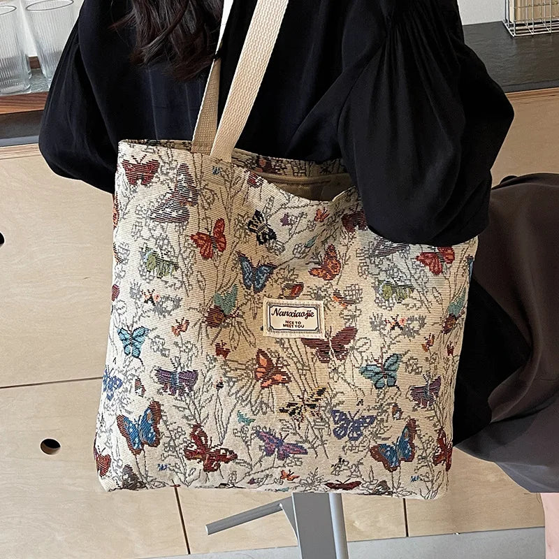 A beige bohemian corduroy tote bag featuring a pattern of colorful butterflies and foliage.