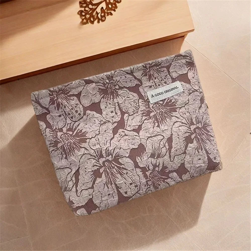 Bolsa de cremallera de lona estampada para guardar electrónica sobre una superficie de madera clara.