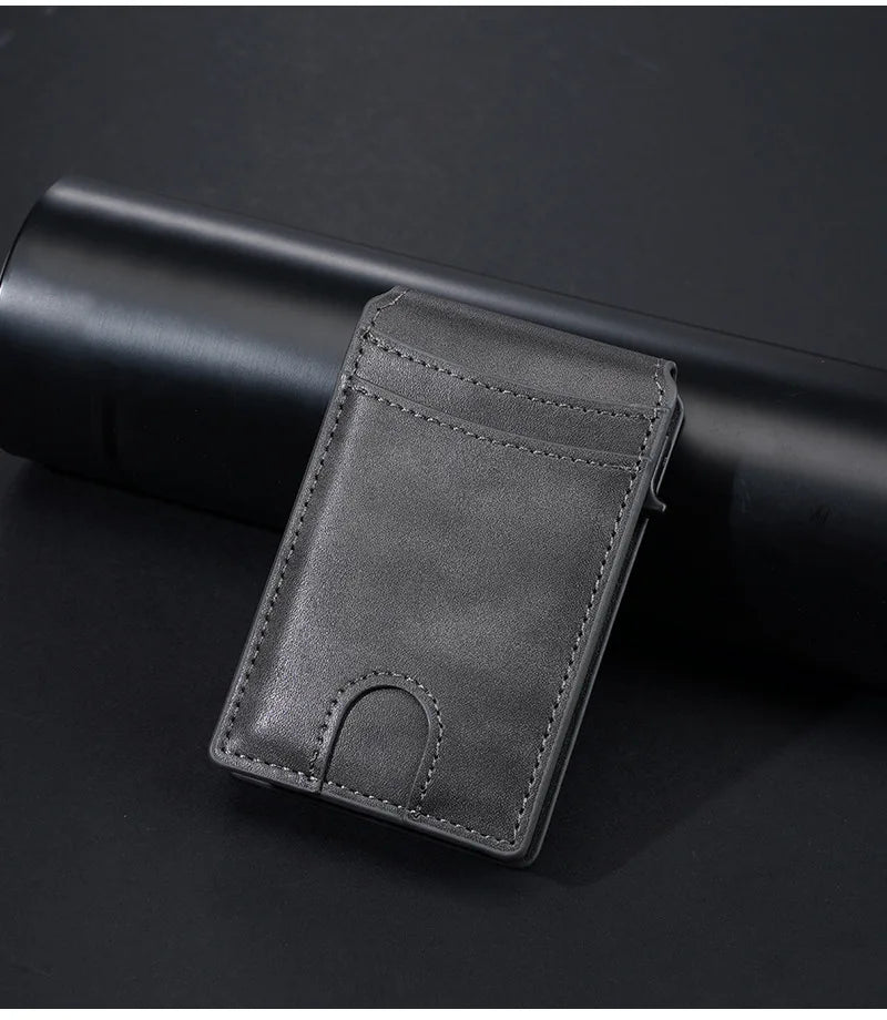 A dark gray PU leather card holder wallet resting on a black cylindrical object.