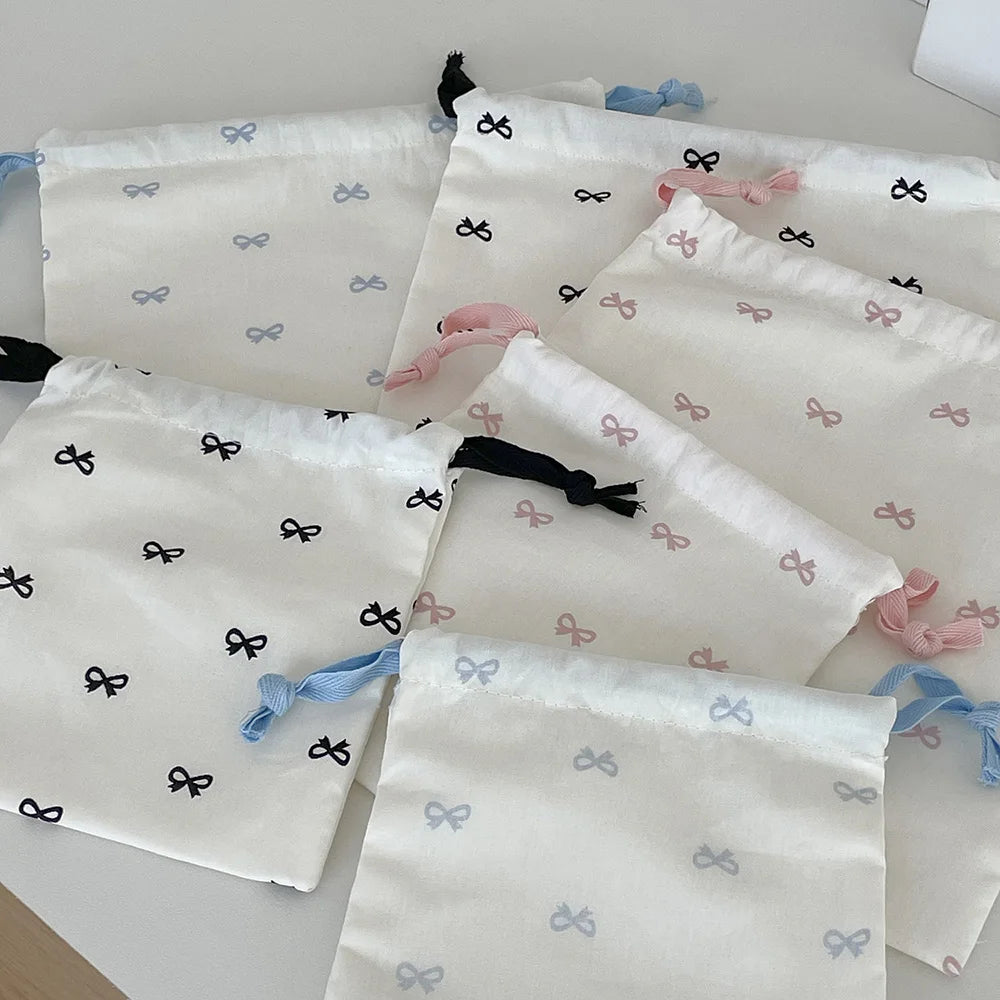 A collection of white canvas makeup bags featuring light blue and pink bowknot designs.