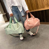A person holds a pink duffel bag with light green straps in a modern indoor setting.