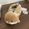 A tan otter plush pencil case is shown lying on a wooden surface, partially open to reveal the interior.