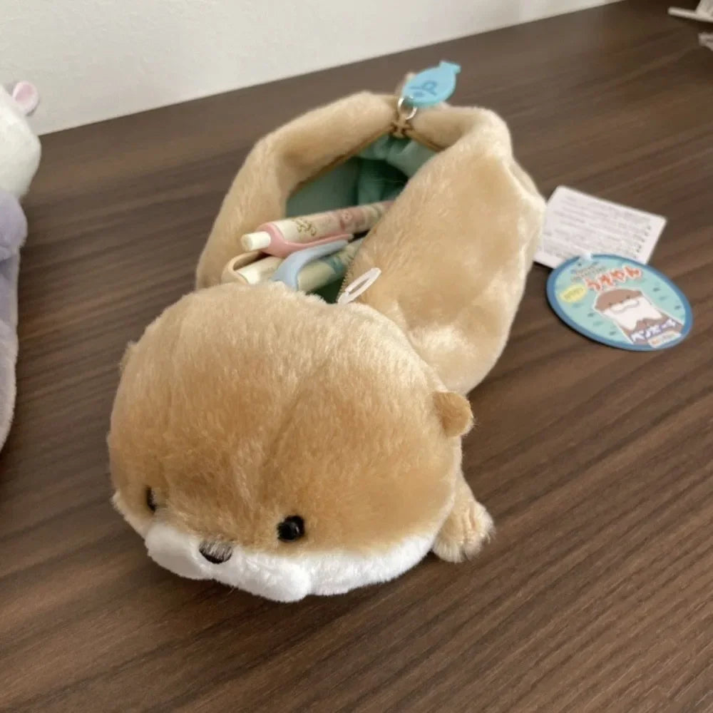 A tan otter plush pencil case is shown lying on a wooden surface, partially open to reveal the interior.