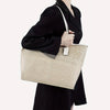 A woman holds a light beige felt purse organizer insert set in her hand against a black coat.
