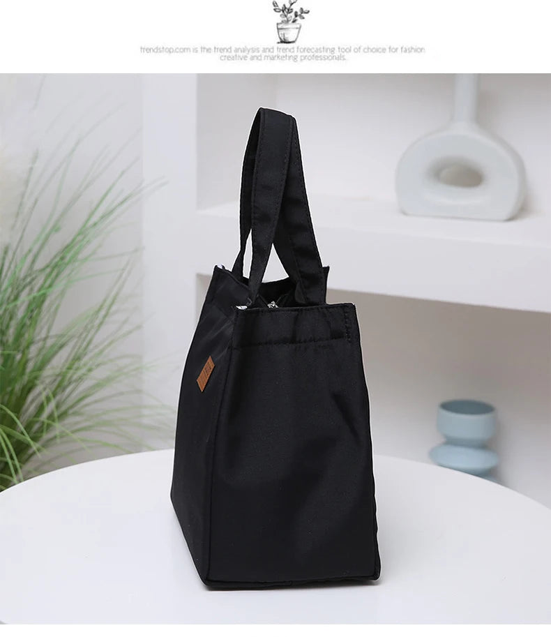 A black durable aluminum foil insulated lunch bag standing on a white surface.