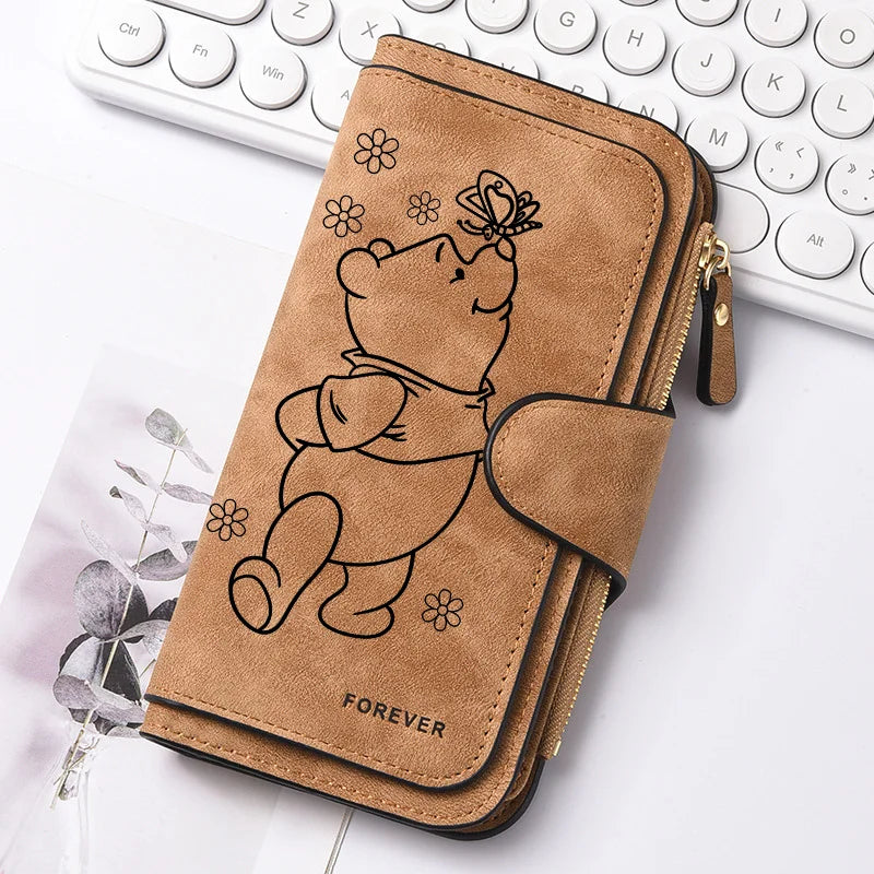 A brown leather zippered coin purse featuring a line drawing of a sleeping bear and a butterfly.