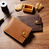 Portefeuille pliable en cuir véritable pour carte d'identité et cartes, posé sur une surface en bois avec des objets connexes
