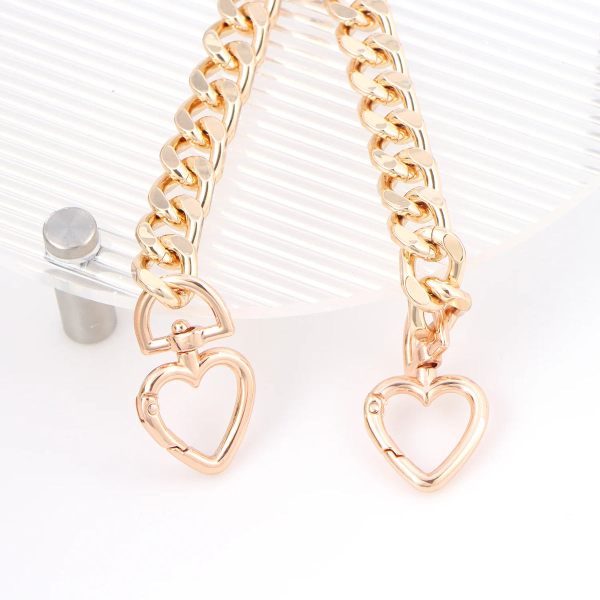 Gold heart-shaped metal purse chain extender displayed on a clear background.
