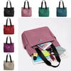 A collection of nylon shoulder tote bags in various colors including black, pink, green, and blue, displayed alongside a larg