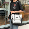 Eine Frau hält ein schwarzes T-Shirt und eine weiße und schwarze Nylon-Tasche mit rotem Herzdesign.