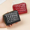 A hand holds a black crocodile print PU leather double zipper wallet and a red crocodile print wallet on a light background.