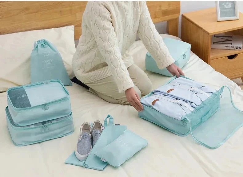A light blue fabric storage organizer set with various pouches and bins is displayed on a bed.