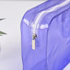 A close-up of a purple transparent PVC travel makeup bag with a white zipper closure.
