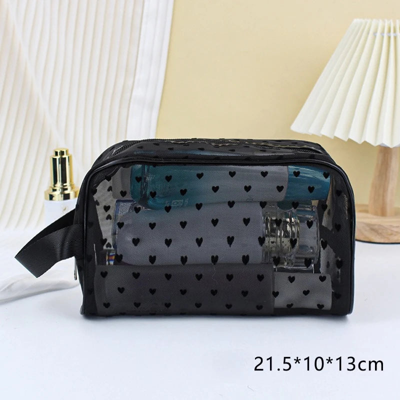 Black mesh transparent makeup storage bag with a strap resting on a white surface.