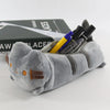 A gray cat-shaped pouch filled with various markers and pens, resting on a black box.