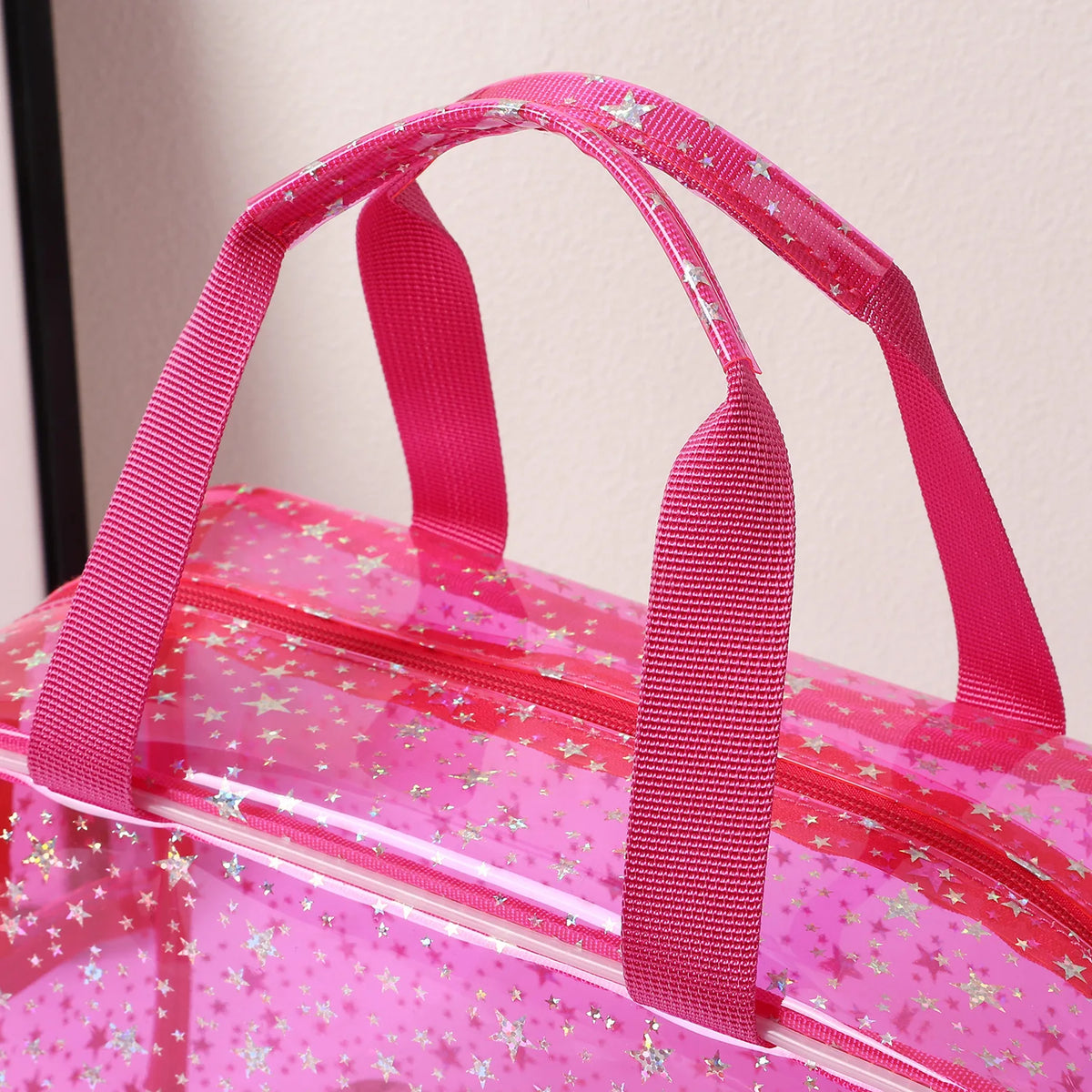 A pink clear waterproof makeup organizer bag with pink straps and glitter accents.