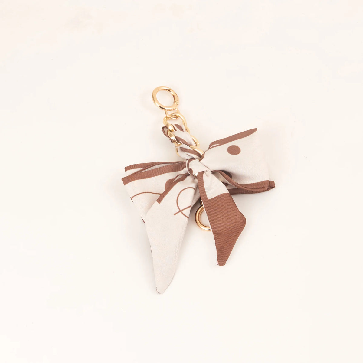 Llavero con lazo de cinta de seda beige y marrón con anillo dorado.