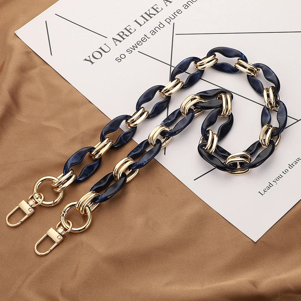 A necklace featuring alternating gold and dark blue acrylic links laid on a piece of paper.