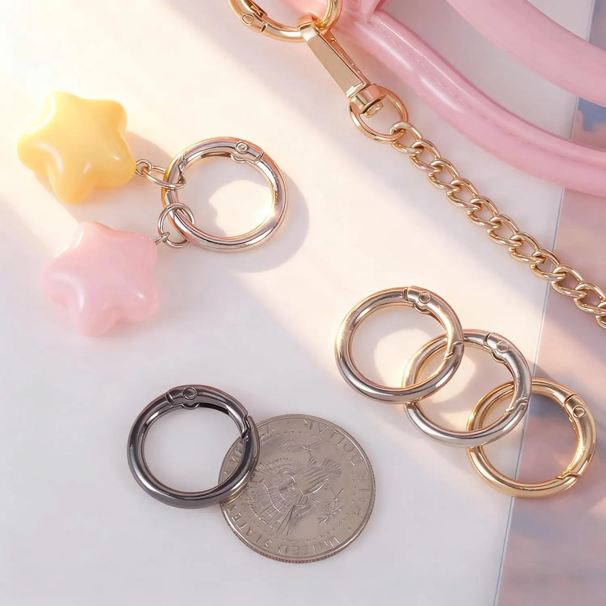A collection of gold and silver metal key rings, clips, and coin-shaped charms are displayed on a white surface.