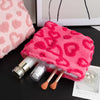 A bright pink plush heart-pattern storage bag for cosmetics and travel with makeup brushes inside.