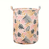 Panier à linge rose en tissu avec motif de feuille tropicale.