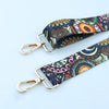 Nahaufnahme eines verstellbaren bestickten Riemens mit blau-violettem Paisley-Muster auf hellem Grund.