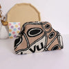 A beige knitted clip bag with a black and white abstract pattern is displayed next to a light yellow fabric piece.