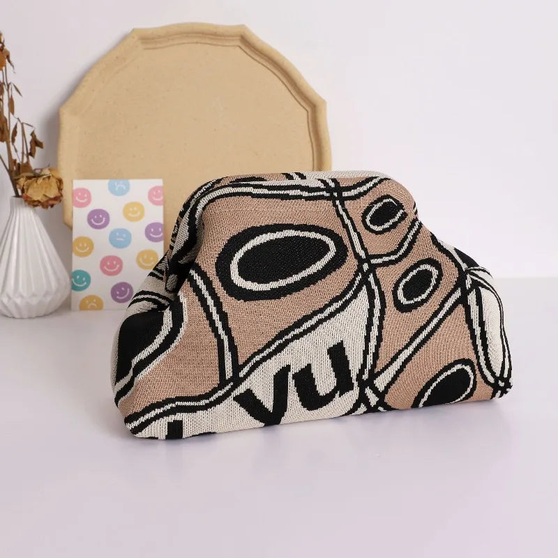 A beige knitted clip bag with a black and white abstract pattern is displayed next to a light yellow fabric piece.