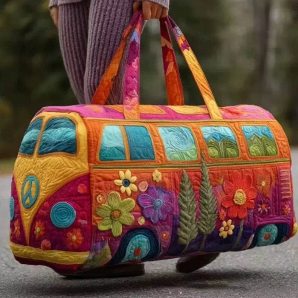 A colorful quilted travel duffle bag featuring a vibrant orange and purple design, held by a person outdoors.