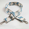 A beige and blue patterned fabric strap with a silver buckle and metal hardware.