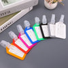 A collection of colorful, customizable luggage tags with white labels and clear plastic holders arranged on a gray surface.