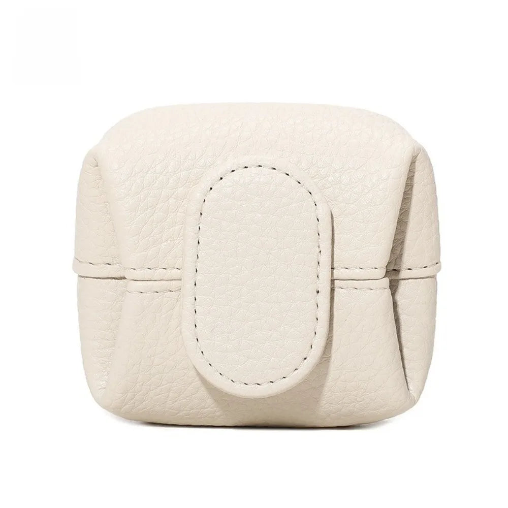 A cream-colored, squarish coin purse with a smooth leather texture and snap closure.