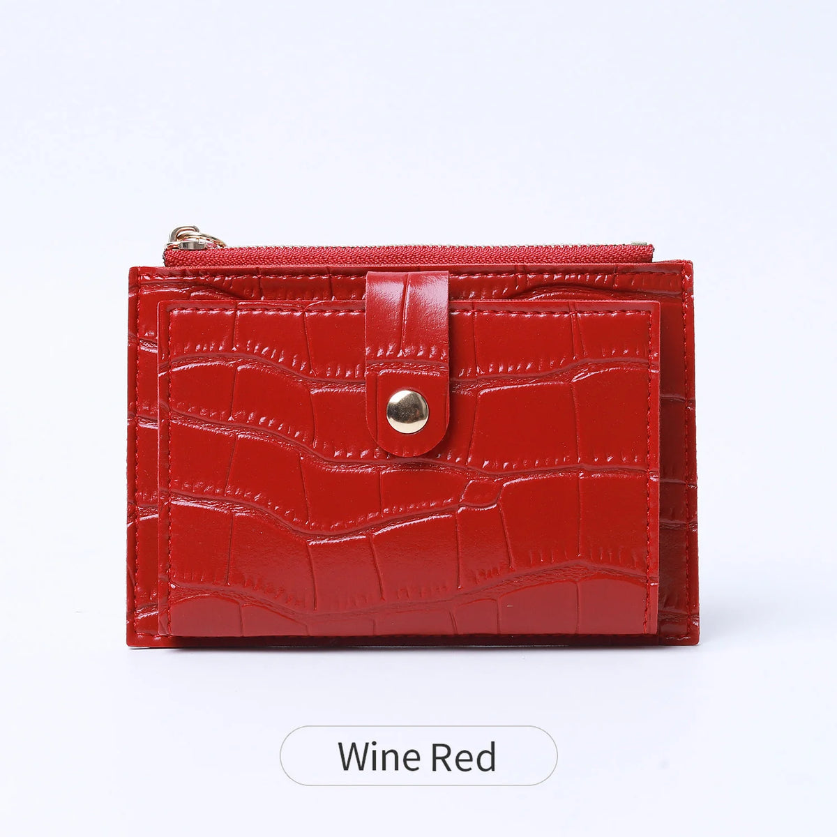 A mini leather card holder in a wine red crocodile pattern with a zipper closure.