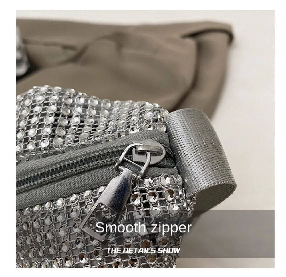 Close-up of a silver rhinestone-embellished crossbody bag with a gray adjustable strap and zipper detail.