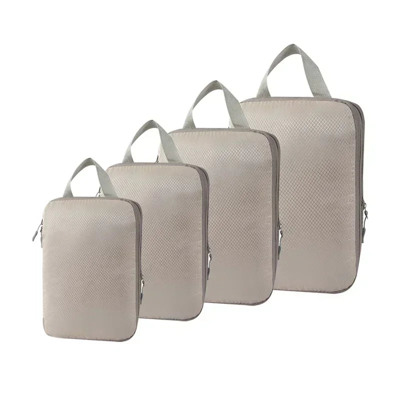 A set of four light beige travel compression packing cubes with fabric texture shown from the front.