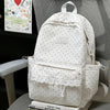 A white polka dot nylon travel backpack with a laptop compartment resting on a gray chair.