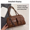 Bolso de cuero sintético marrón retro con correa de cuero y herrajes decorativos sobre fondo blanco.
