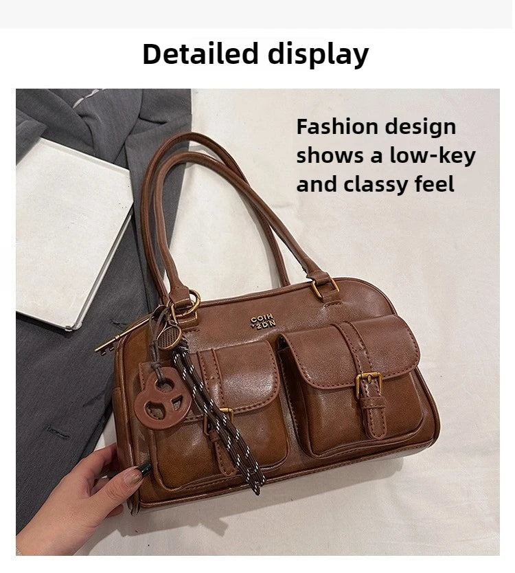 Bolso de cuero sintético marrón retro con correa de cuero y herrajes decorativos sobre fondo blanco.