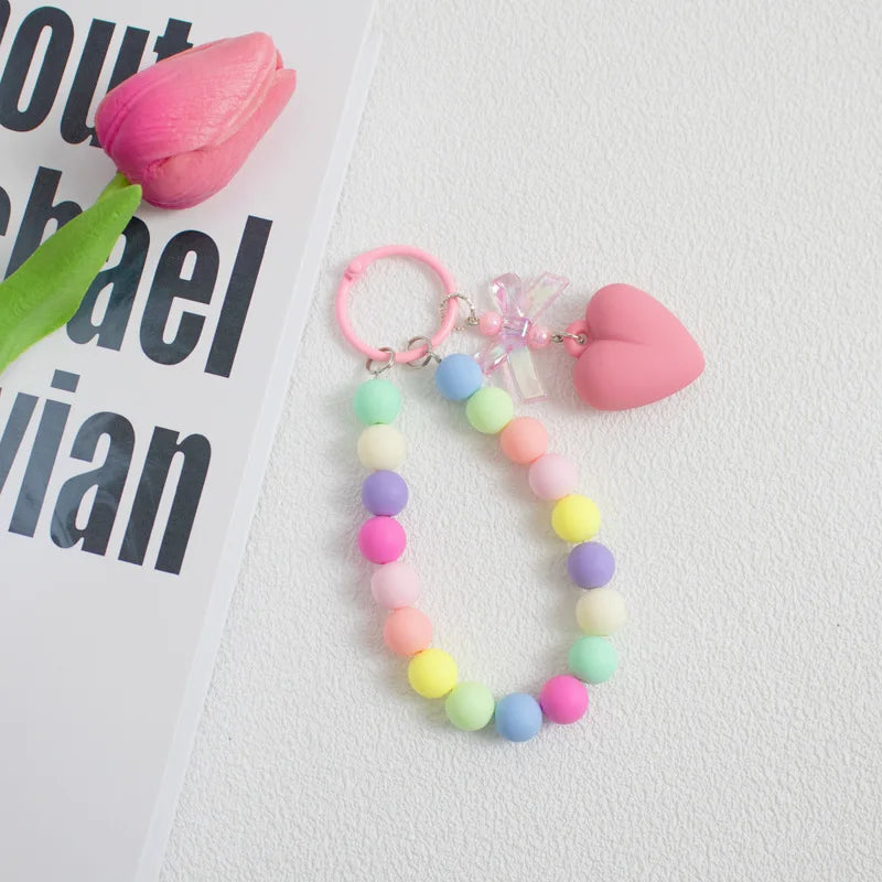 A colorful bead keychain featuring pink and green beads and a heart charm on an O-ring clip.