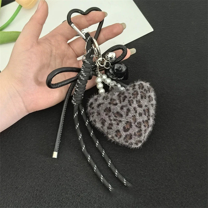 A black leather charm keychain featuring a heart shape and leopard print faux fur.