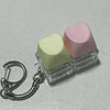 A clear plastic fidget toy keyboard with three pastel colored buttons, including light green and pink.