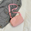 A pink nylon cross-body waist bag with a strap is shown against a white background.