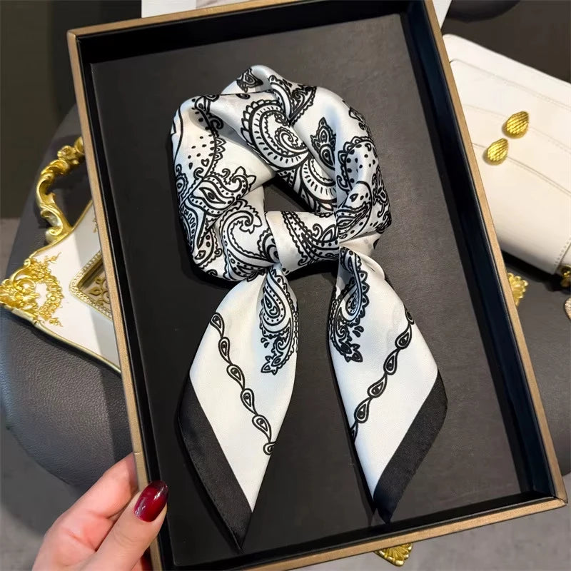 A black framed photo displays an elegant paisley silk hair scarf tied in a bow.