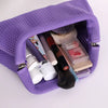 A purple knitted clip bag is open, displaying various makeup and beauty tools inside.