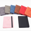 A collection of ten passport holders in various shades of gray, blue, brown, and red leather.