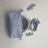 A light blue waterproof nylon crossbody bag with a detachable mini pouch and accompanying straps.