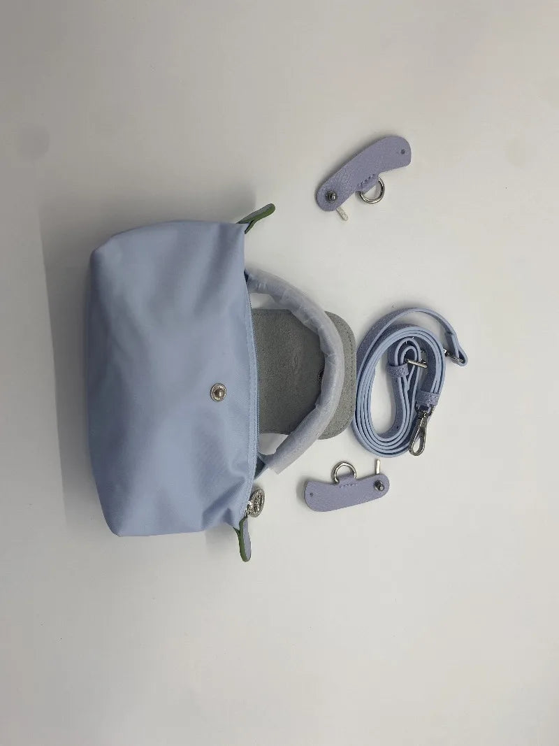 A light blue waterproof nylon crossbody bag with a detachable mini pouch and accompanying straps.